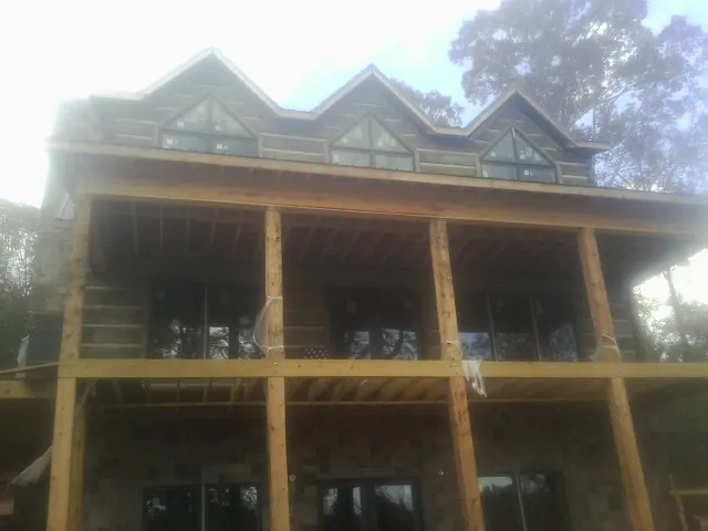 Dormers and porch framing on a large log home under construction — Roof Coating work by our crew in Pinehurst